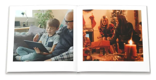 An open photo book: a grandfather and grandson with a tablet, and a family at Christmas